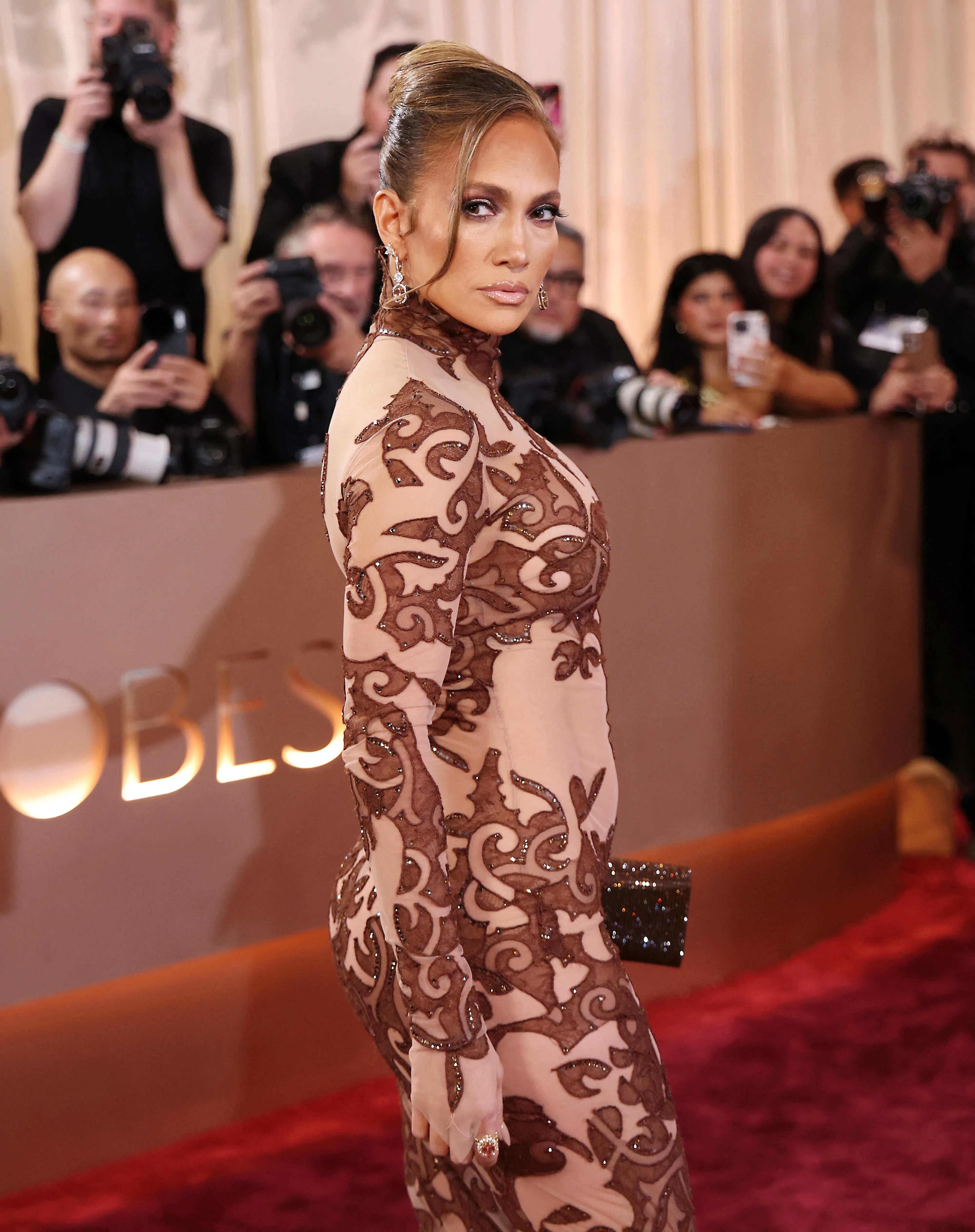 Jennifer Lopez in a sheer, long-sleeved gown with brown embroidered details at the Golden Globe Awards.