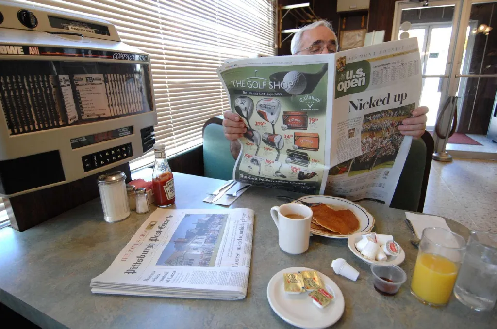 A man at a diner reads a newspaper with a