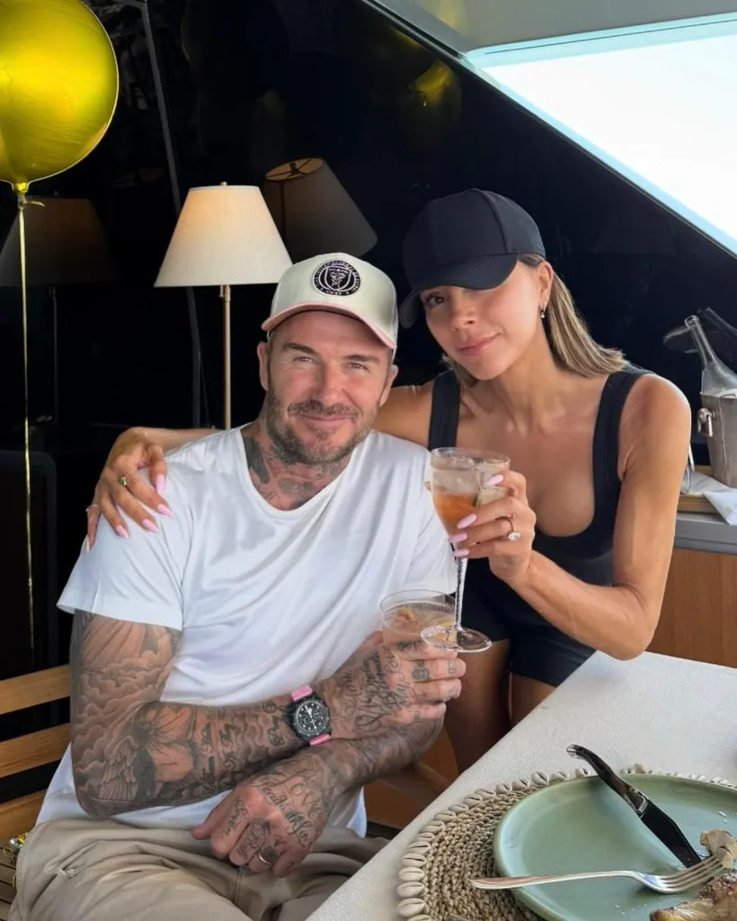 Victoria and David Beckham posing on a yacht with drinks.