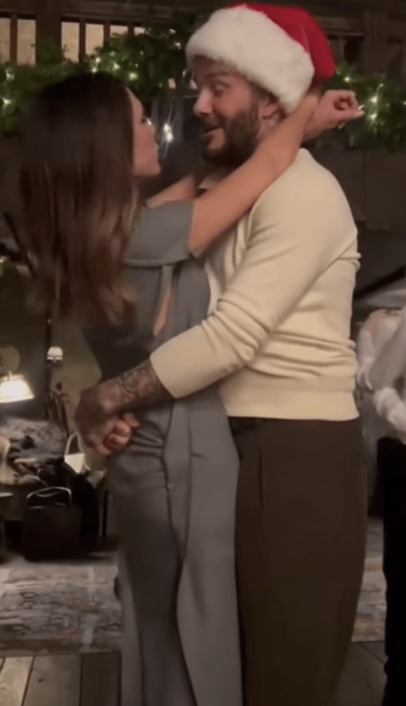 Victoria Beckham, in a grey dress, and David Beckham, in a cream sweater and black pants, dancing.