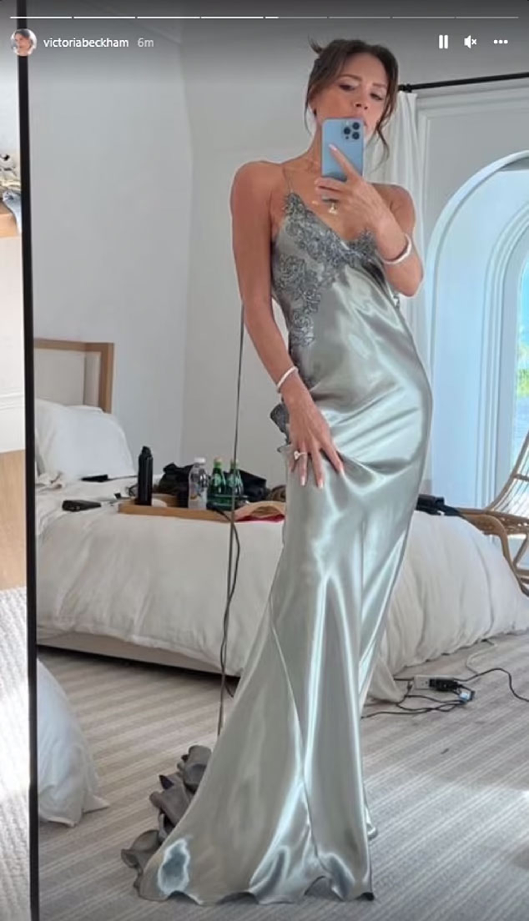 Victoria Beckham models a long, light blue silk gown with lace details in a mirror selfie.