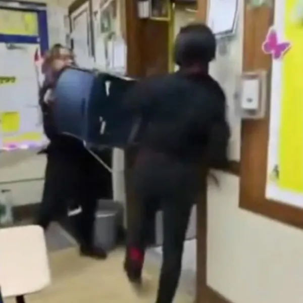 An object, appearing to be a box cutter, can be seen falling from the student’s hand as. the pair run out of the classroom.