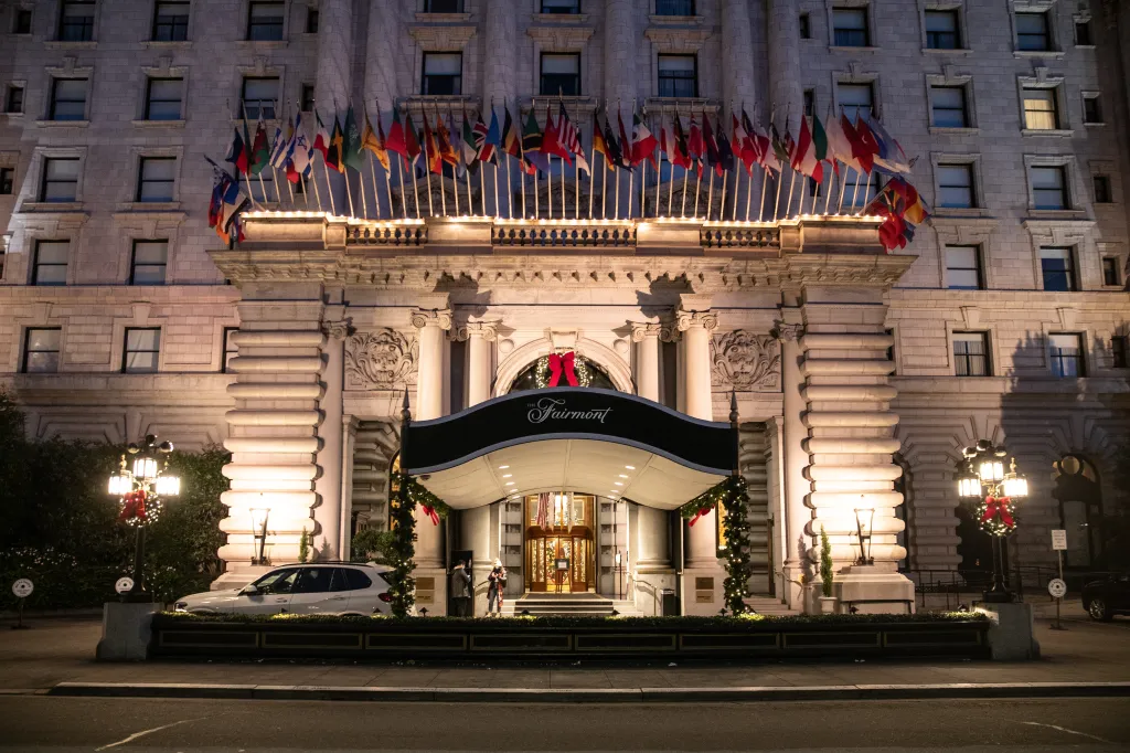 The Fairmont Hotel with flags of various nations displayed above its entrance, decorated for the holidays.
