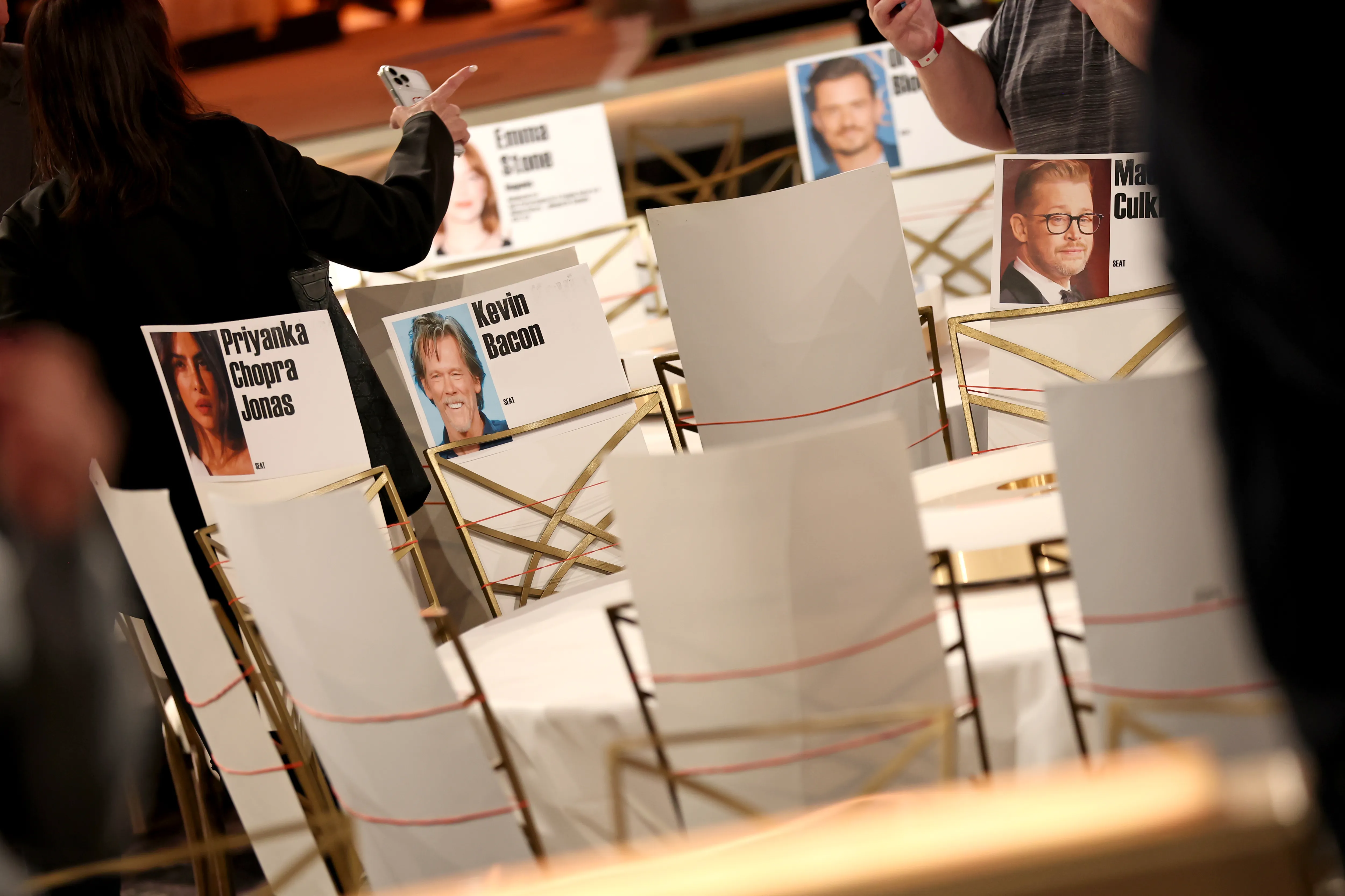 Chair place cards with celebrity names including Priyanka Chopra Jonas, Kevin Bacon, Emma Stone, and Macaulay Culkin at the Golden Globes.