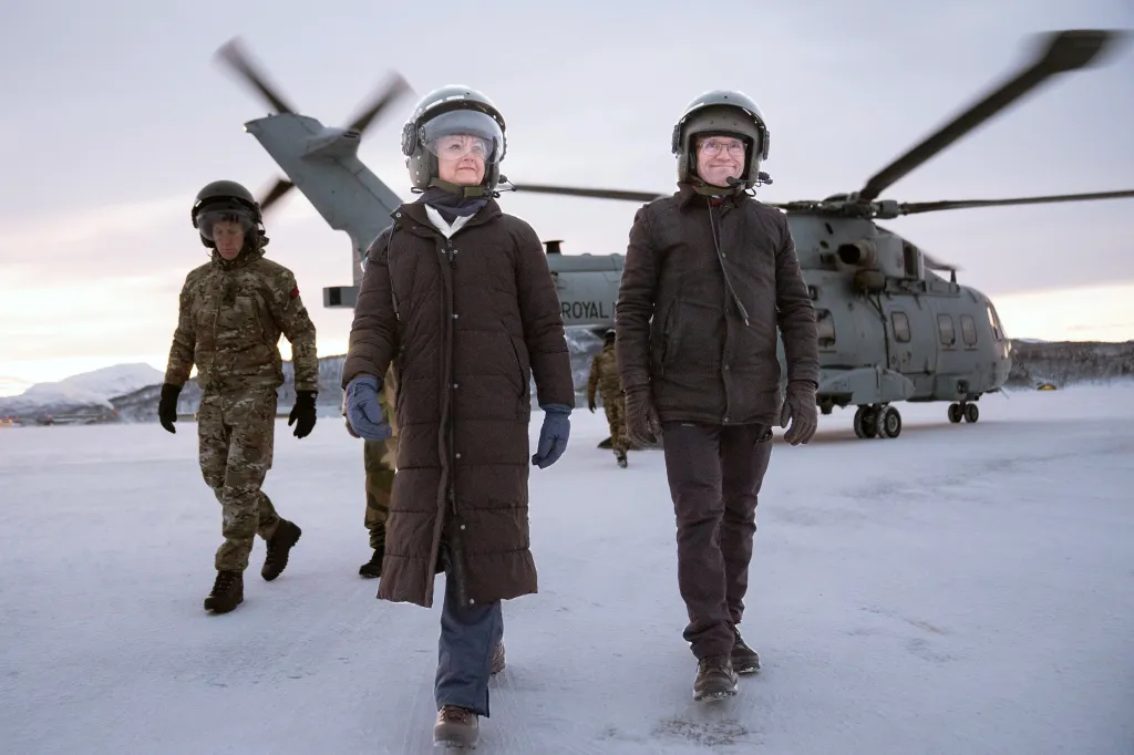 Yvette Cooper and Barth Eide walking from a helicopter in cold weather gear on a snowy field.