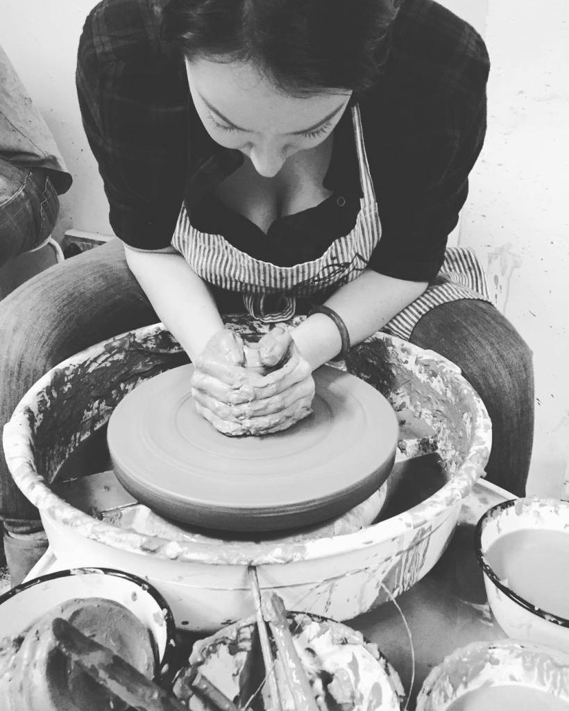 A woman creating ceramics on a pottery wheel.