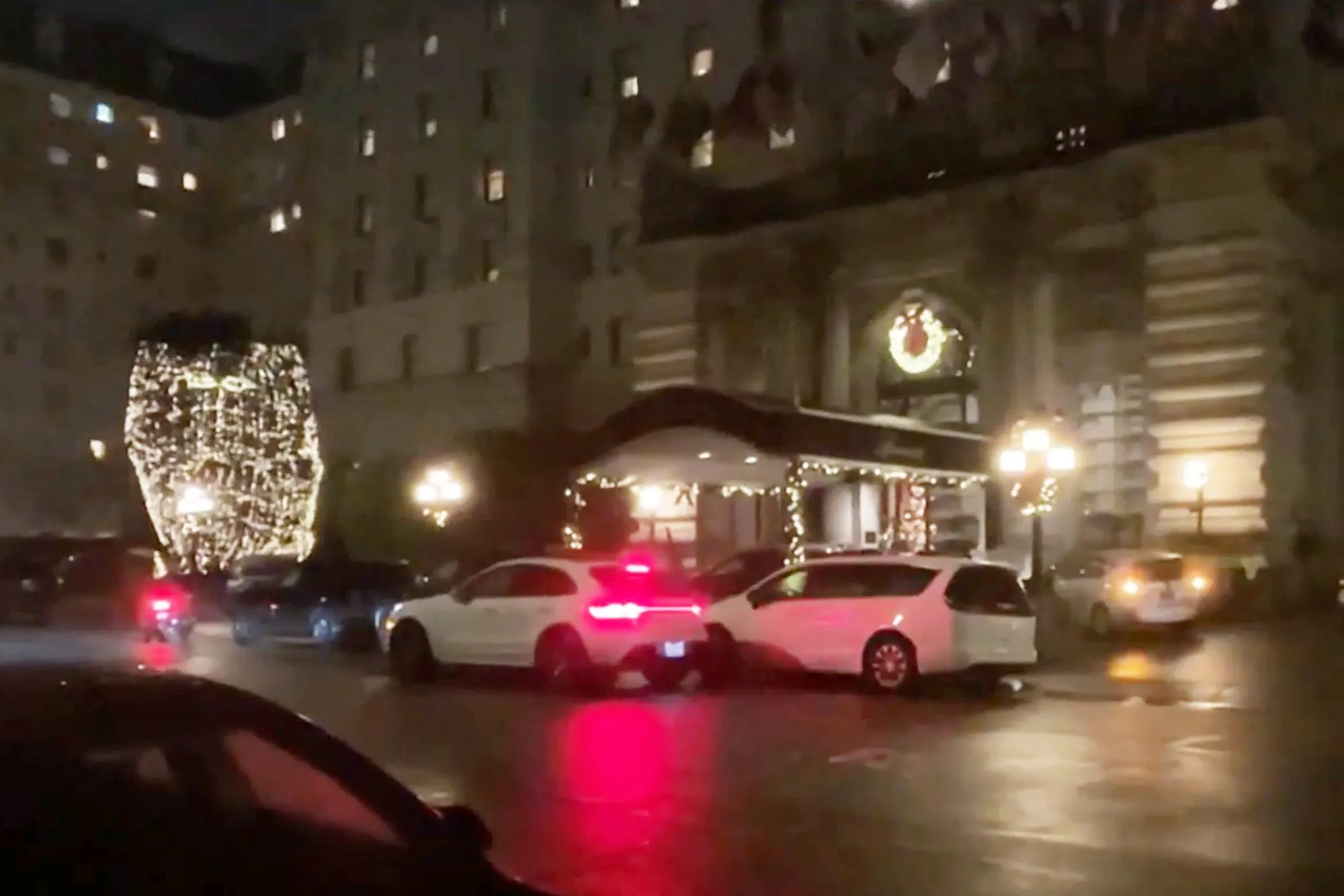 Exterior of the Fairmont San Francisco hotel at night, with Christmas decorations including a large wreath and lights on a tree.