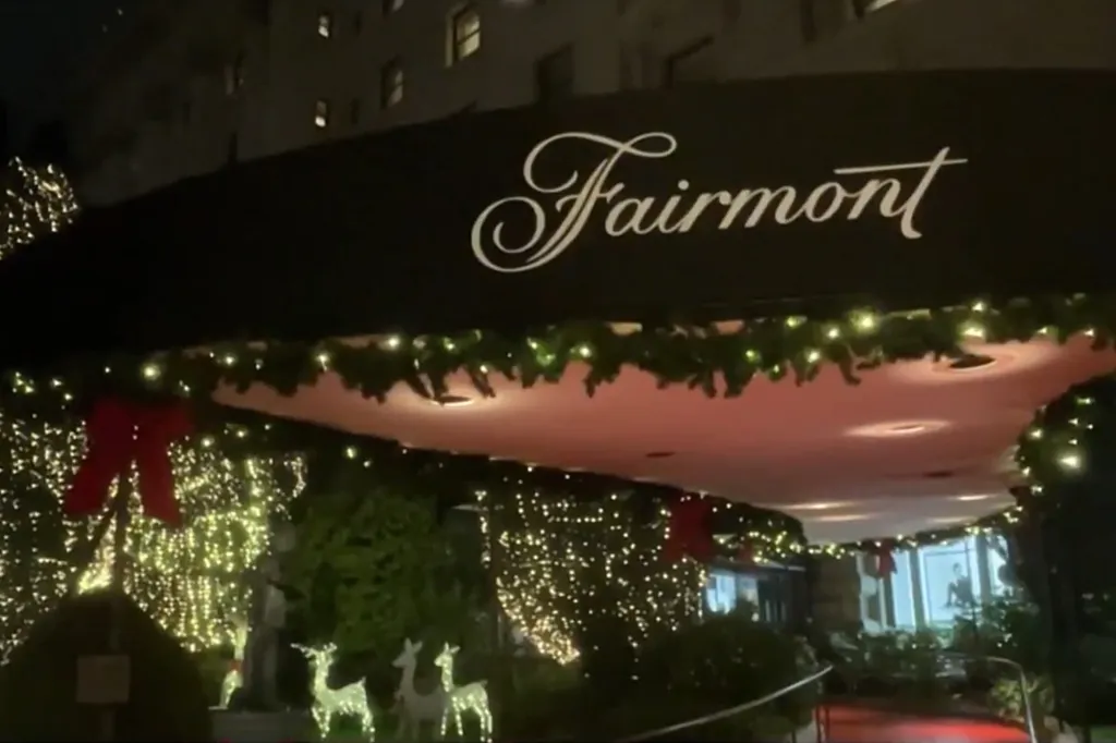 Exterior of the Fairmont Hotel at night, decorated with holiday lights, garland, and red bows.