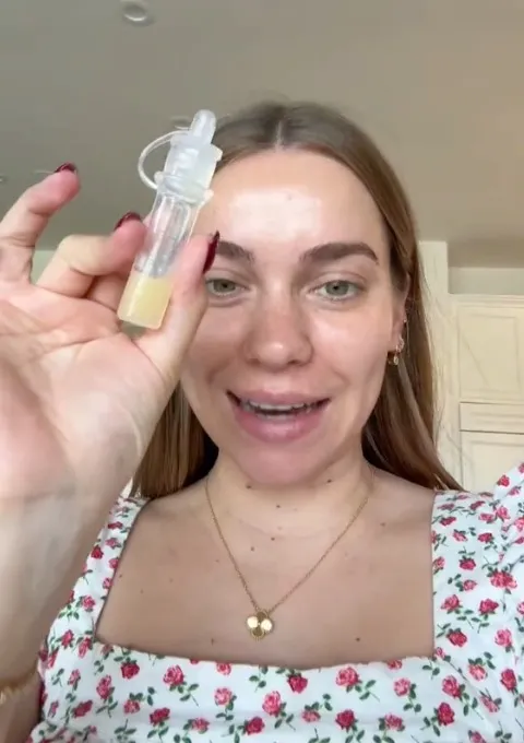 Woman holding a small vial of pumped colostrum.