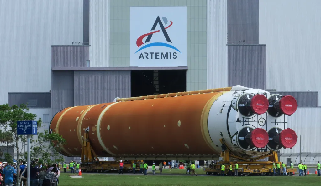 Workers transporting the 212-foot-tall SLS core stage for the Artemis II moon rocket to the Vehicle Assembly Building.