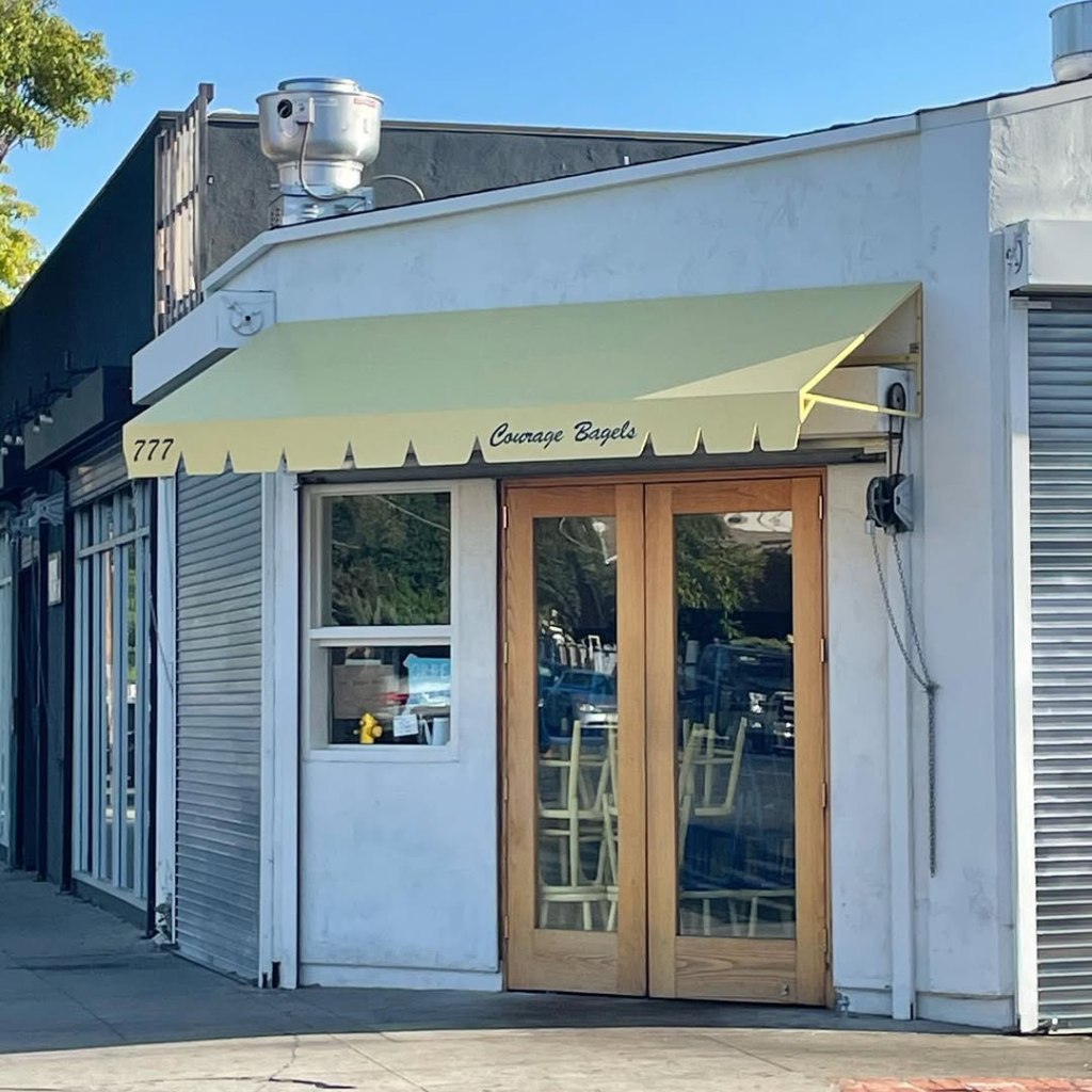 Exterior of Courage Bagels in Silverlake, showing the storefront with a yellow awning.