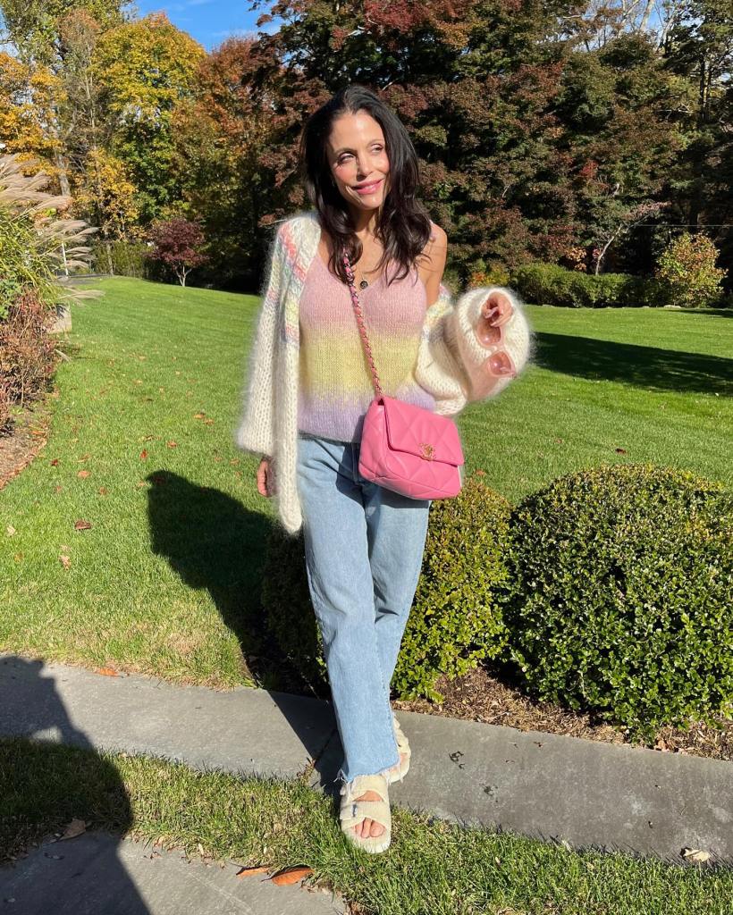 Bethenny Frankel posing outdoors in a colorful sweater and light-wash jeans.