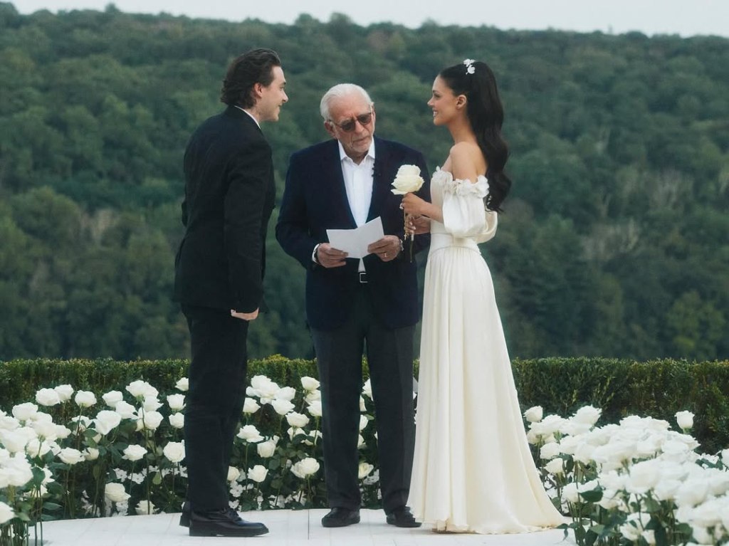 Brooklyn Beckham, in a black suit, and Nicola Peltz, in a cream wedding gown, during their vow renewal with Nelson Peltz, in a black suit and white shirt.