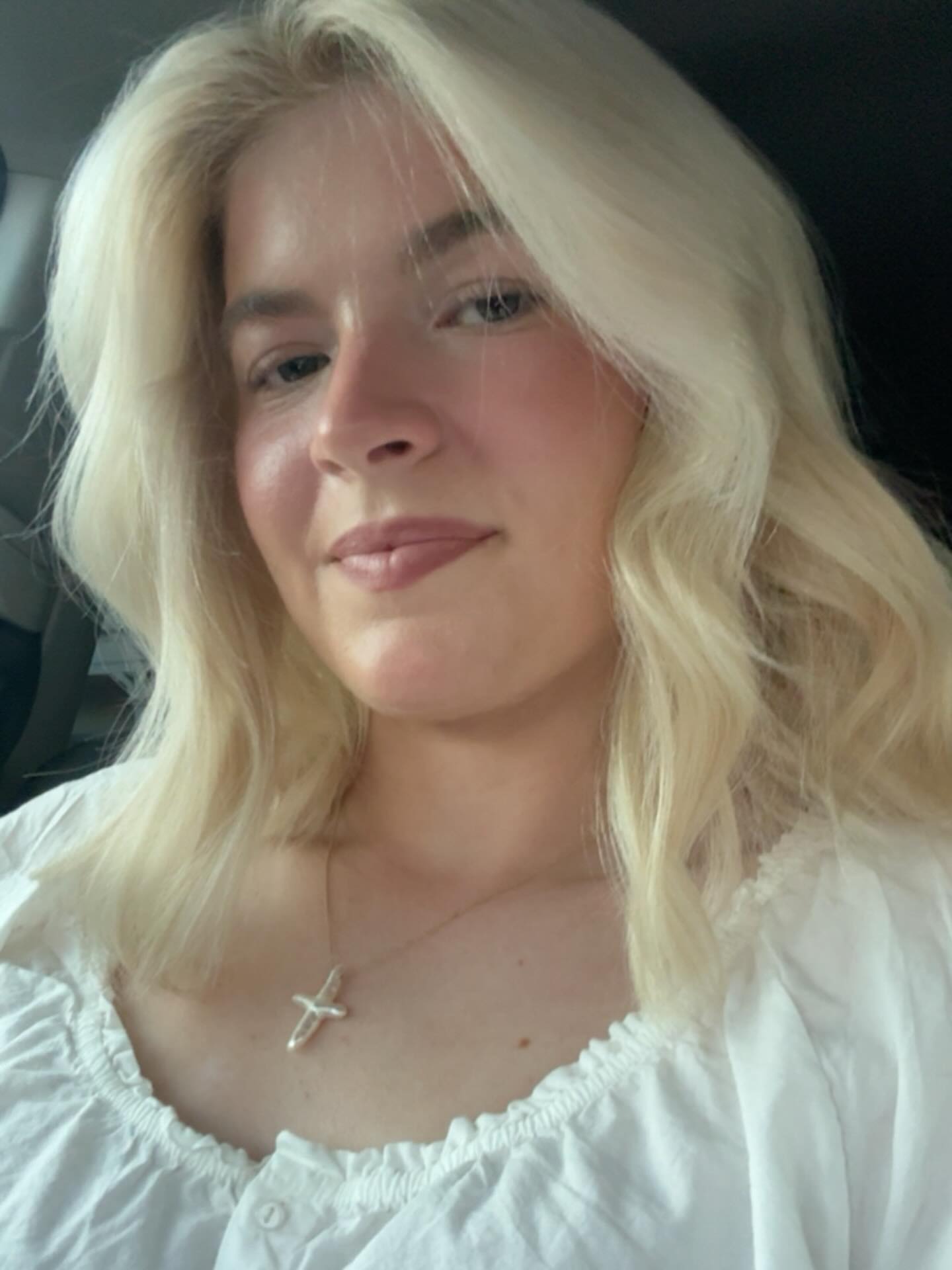 Lola Sheen with blonde hair and a white ruffled top.