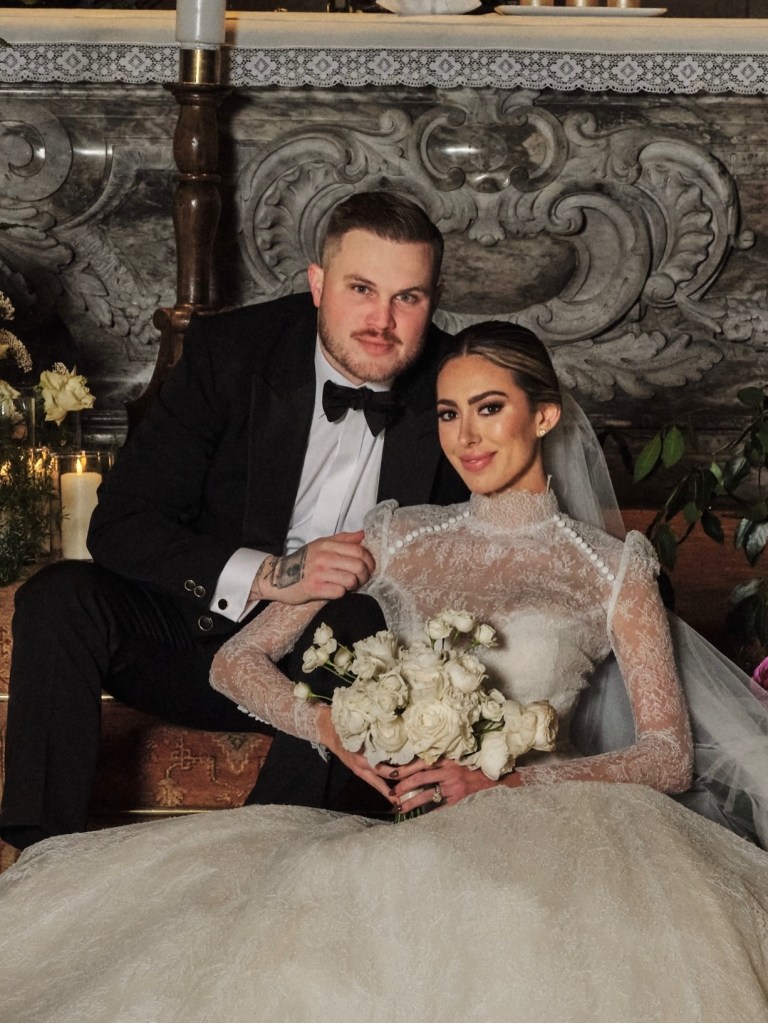 Samantha and Zach Bryan posing in wedding attire.