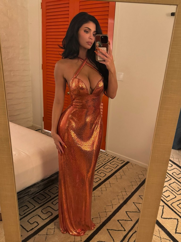 Kylie Jenner taking a mirror selfie in a sparkly orange dress.
