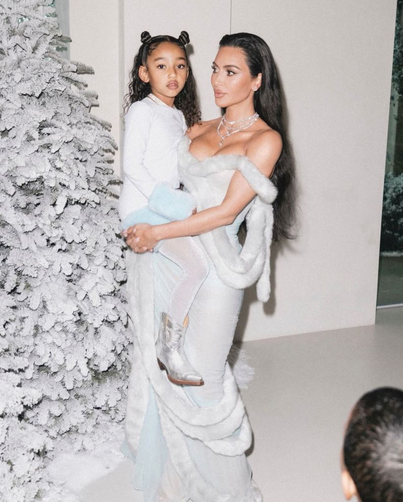Kim Kardashian holding Chicago West next to a flocked Christmas tree.