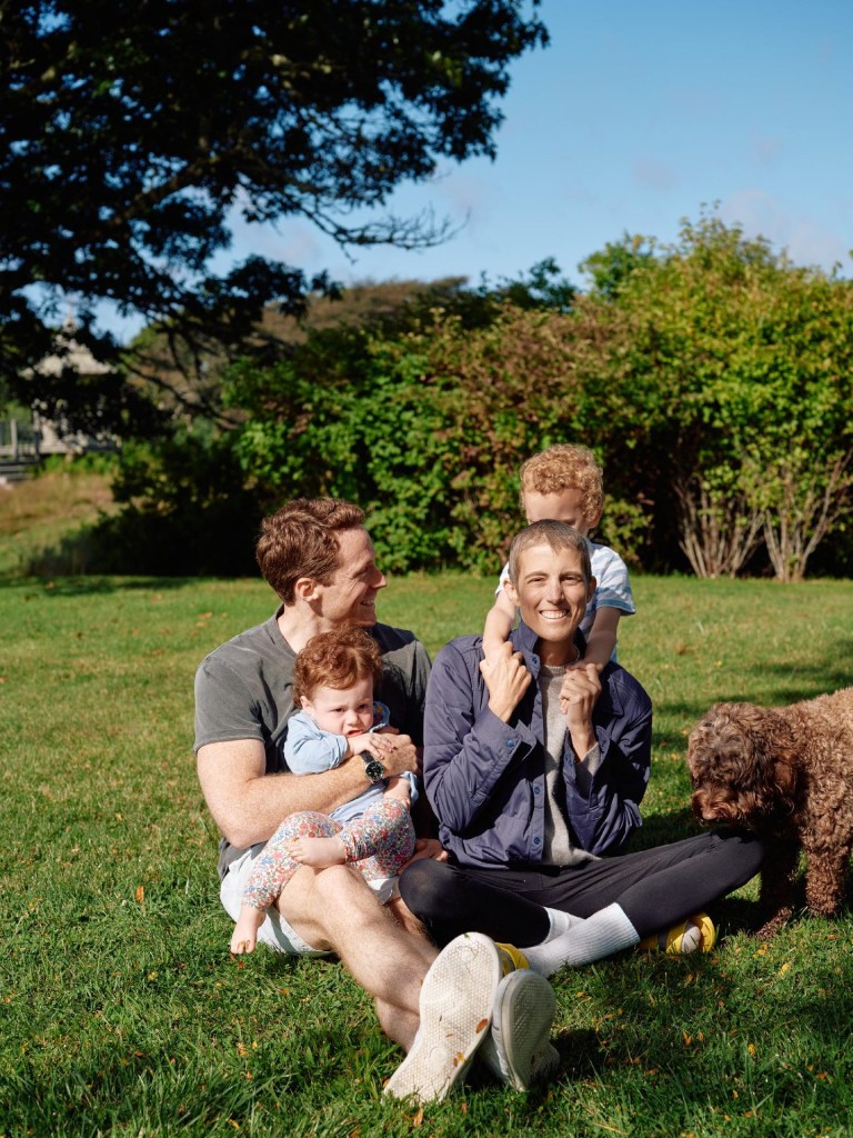 Tatiana Schlossberg, in a grey jacket and black leggings and a cream t-shirt, with Dr. George Moran, in a grey t-shirt and khaki shorts, holding Josephine Moran, in a blue top and floral leggings, and Edwin Moran in a white t-shirt and their dog.