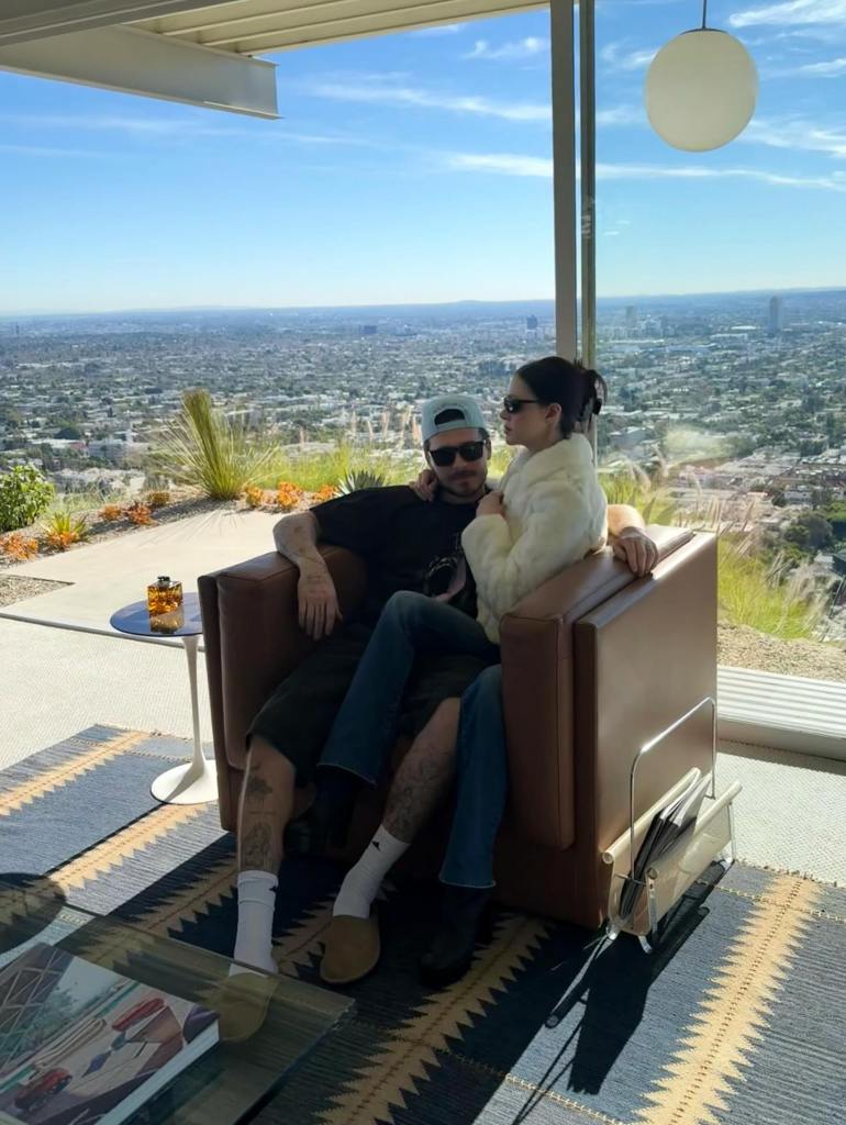 Nicola Peltz and Brooklyn Beckham sitting in a chair overlooking a city.