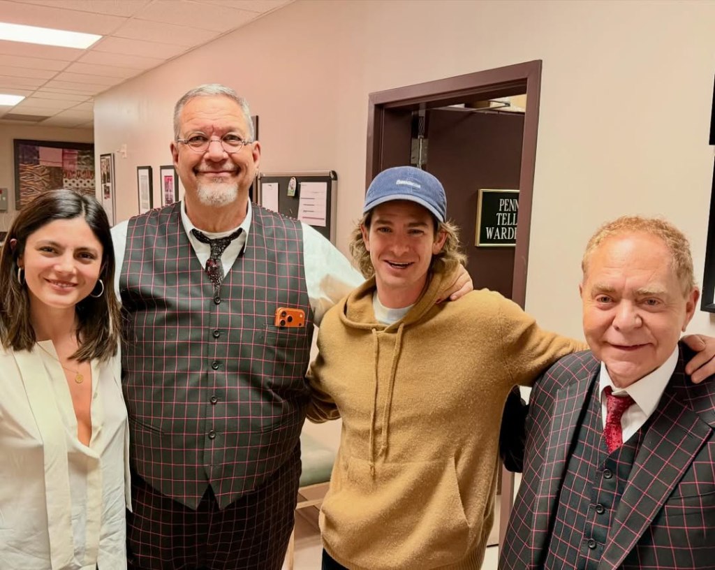 Andrew Garfield with blonde hair poses with Penn Jillette, Teller, and Monica Barbaro.