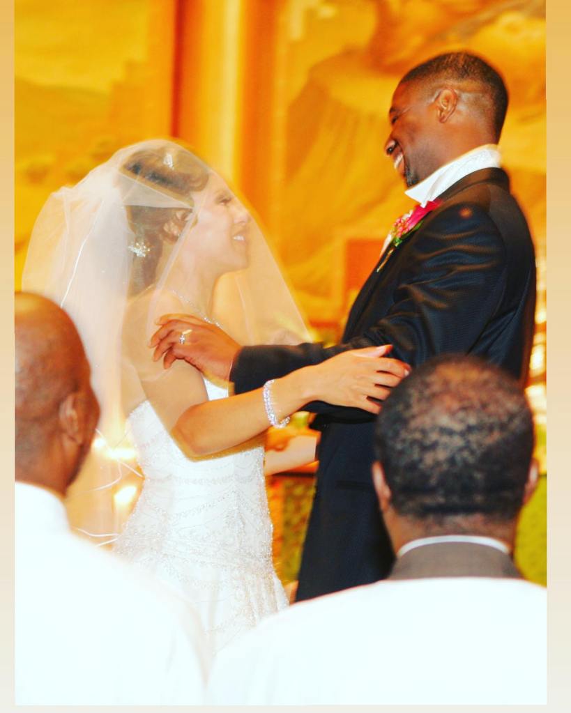 Sheinelle Jones, in a wedding gown, and her husband Uche Ojeh, in a black suit and white shirt, smiling at each other at their wedding.
