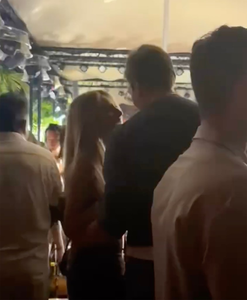 Alix Earle and Tom Brady talking to each other at a gathering.