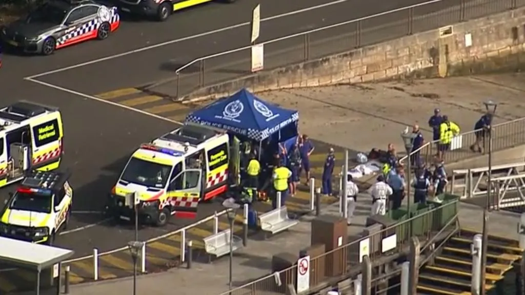 Emergency services on a dock with a medical tent, ambulances, and police vehicles.