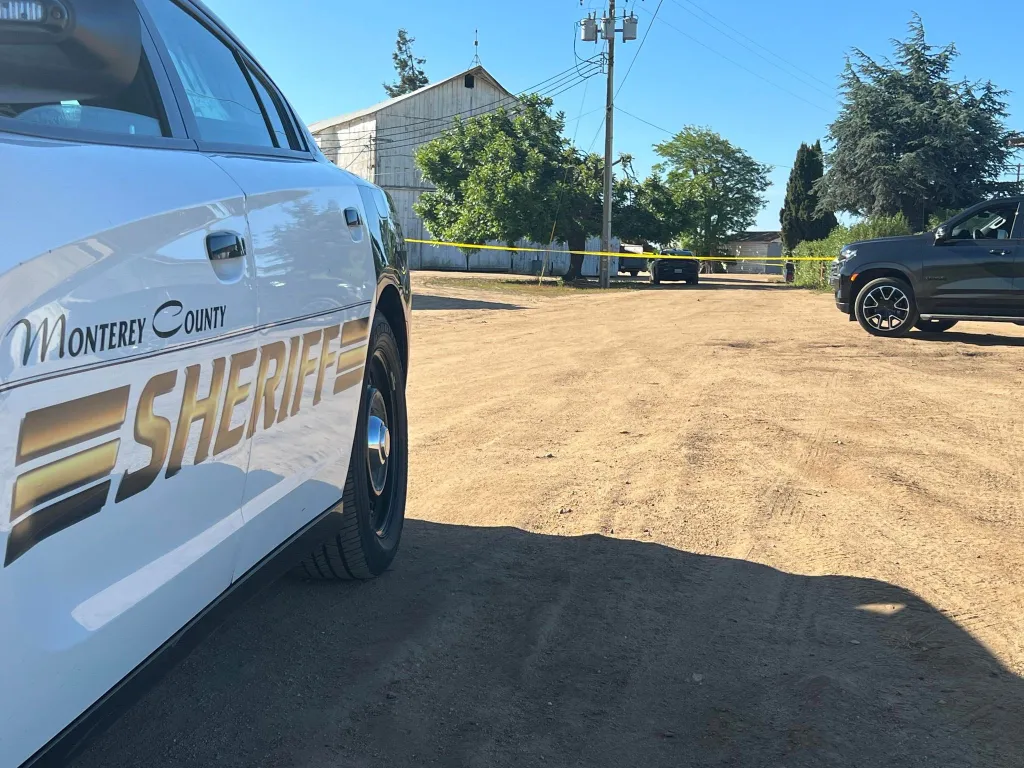 A Monterey County Sheriff's patrol car at a crime scene blocked off with yellow tape.