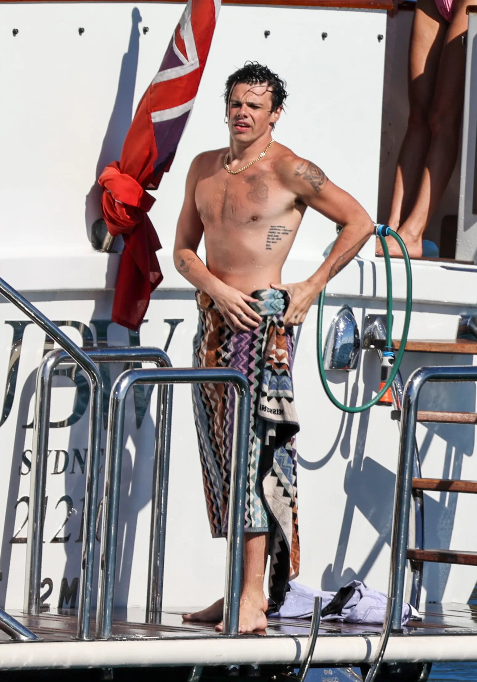 Yungblud on a yacht in Sydney, wrapped in a colorful towel around his waist.