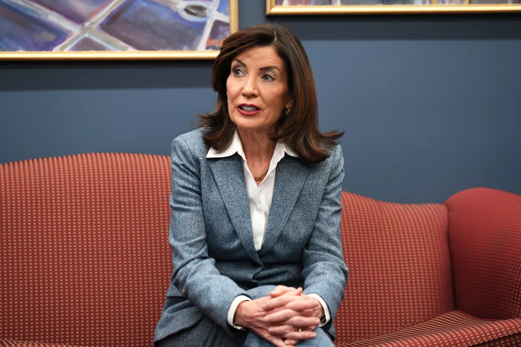 New York Governor Kathy Hochul sitting on a red couch during a meeting.