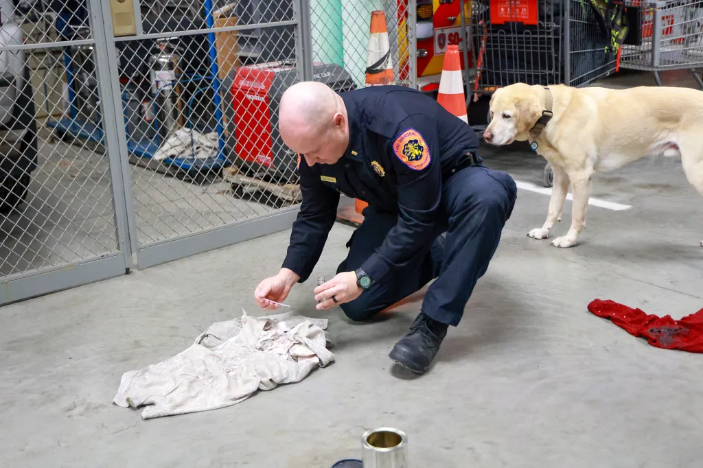 Lieutenant Joseph Battaglia of the Nassau County Fire Marshal K9 unit preparing for a training session with a yellow lab.
