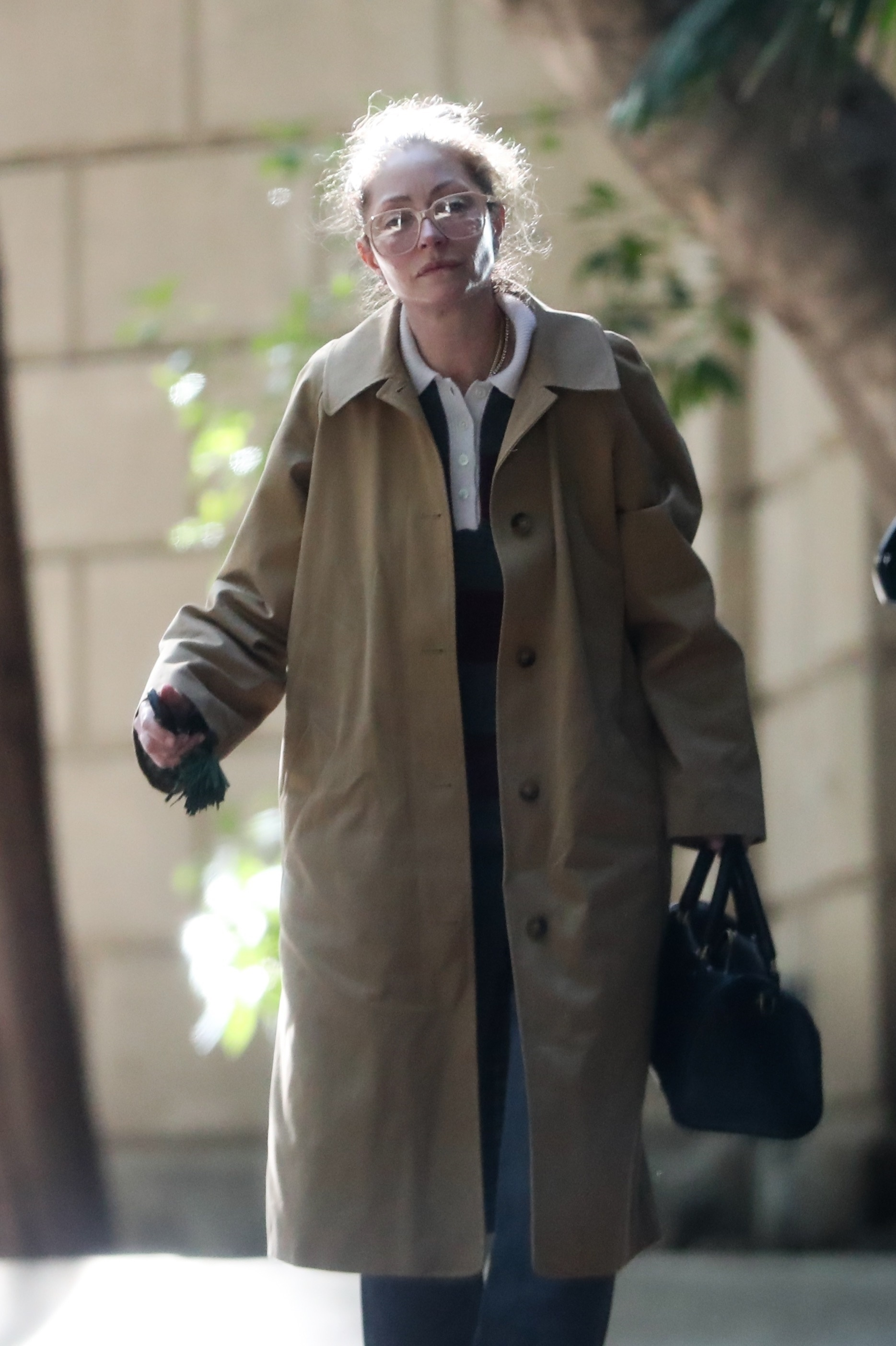 Rebecca Gayheart in a camel trench coat, oversized glasses, and a somber expression, visiting Eric Dane's home.