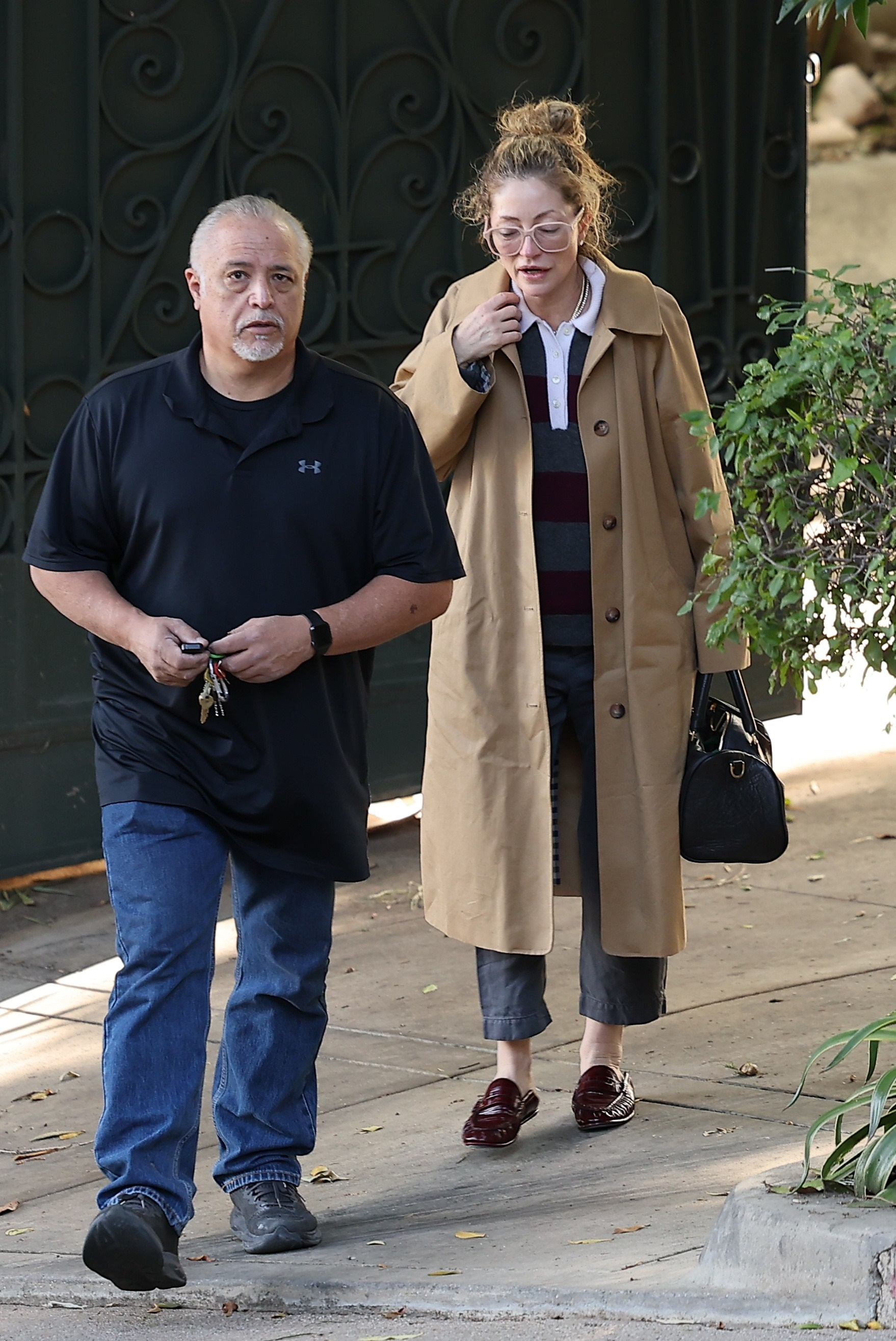 Rebecca Gayheart, appearing somber, walking next to an older man with white hair.