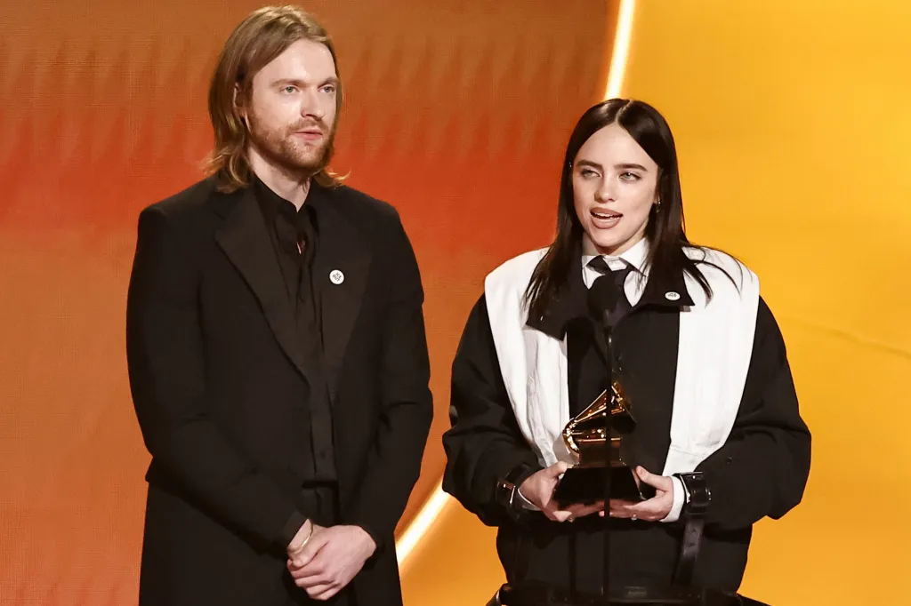 Finneas O'Connell and Billie Eilish on stage with a Grammy award.