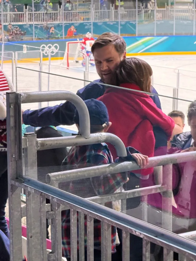 A man holding a child in the stands of an ice hockey game.