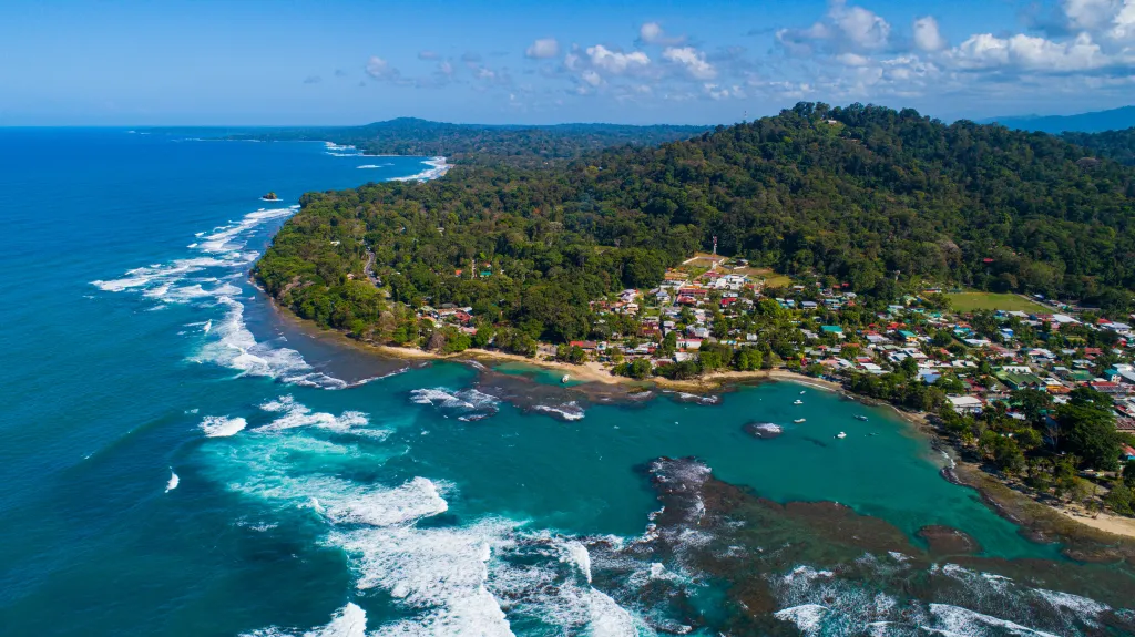 Aerial view of Puerto Viejo, Costa Rica, a Caribbean town along a coastline of lush green forest.