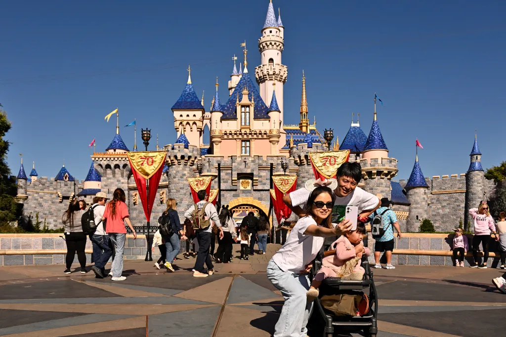 A family taking a selfie in front of Sleeping Beauty Castle at Disneyland.