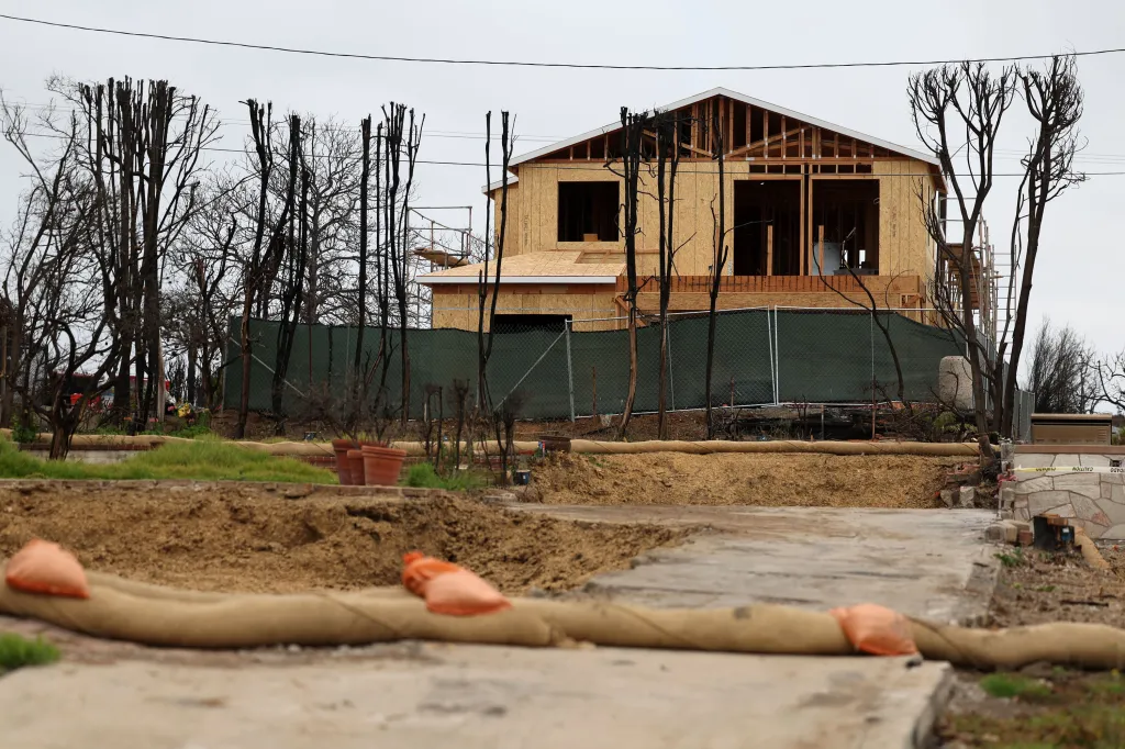 A new house under construction on 15256 De Pauw St., with a backdrop of charred trees from a recent fire.