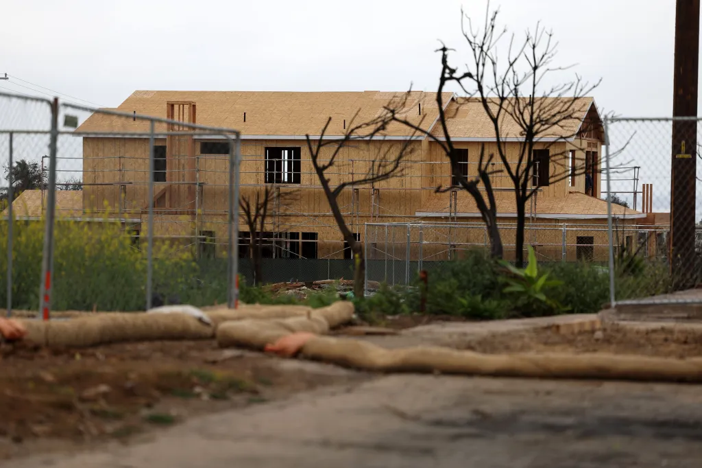 A partially constructed house behind a chain-link fence.