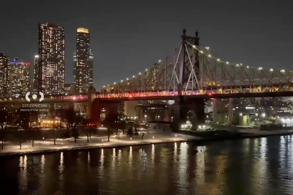 Nighttime view of the Queensboro Bridge over the East River with the New York City skyline in the background.