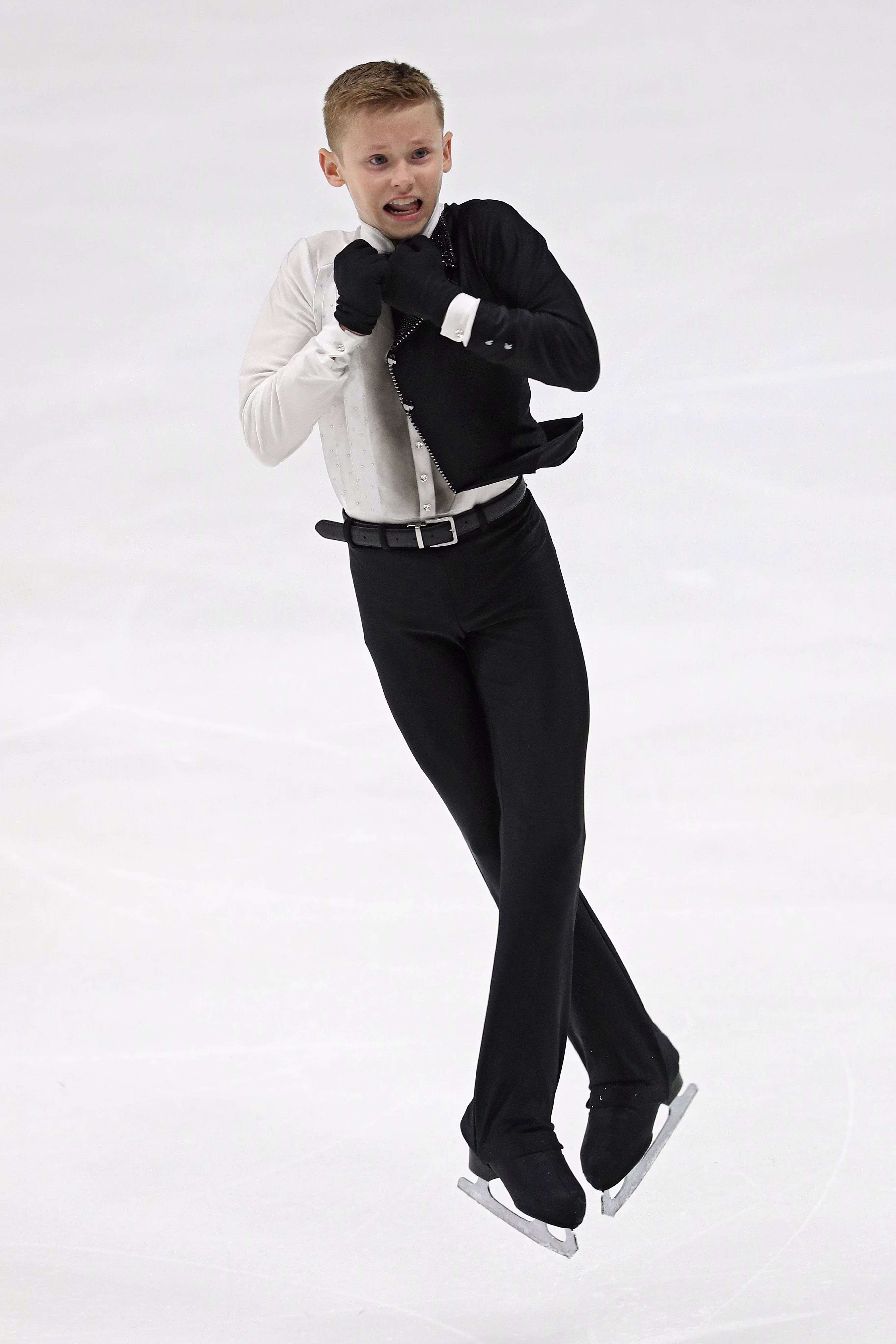 photo of boy with arms pulled in and legs crossed in performance on ice rink