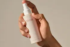 A man's hand holding a bottle of hair growth solution. 