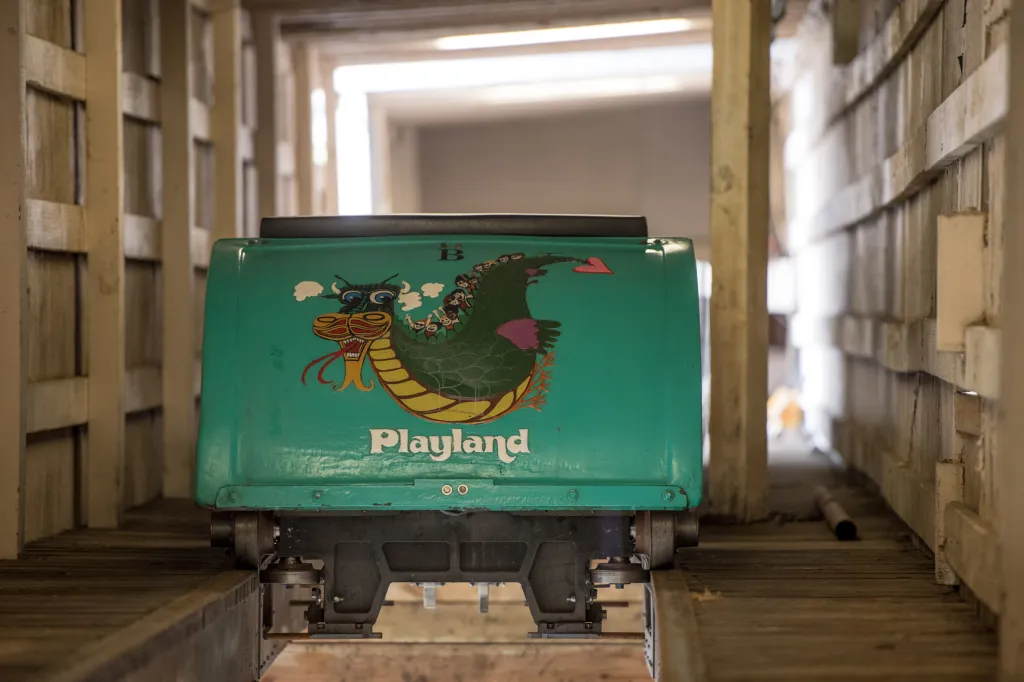 A teal Dragon Coaster car from Playland amusement park sits in a wooden service tunnel.