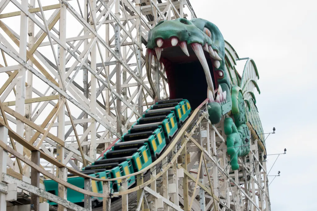 The Dragon Coaster at Playland amusement park with a train of cars heading into the open mouth of a green dragon structure.