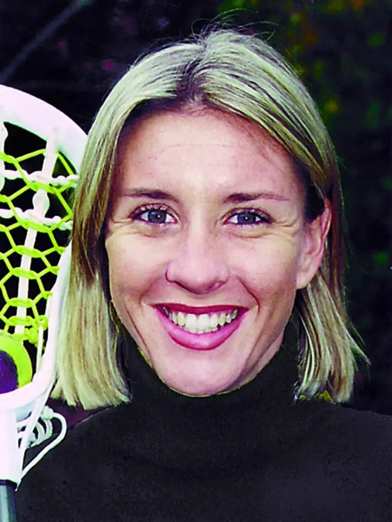 St. Mary's College lacrosse coach Diane Whipple smiling, with a lacrosse stick head visible to her left.