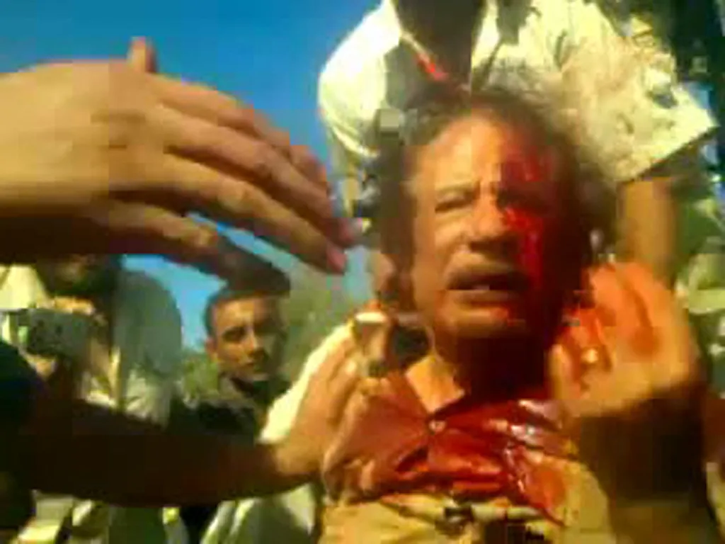 Moamer Kadhafi, bloodied, captured by National Transitional Council fighters.