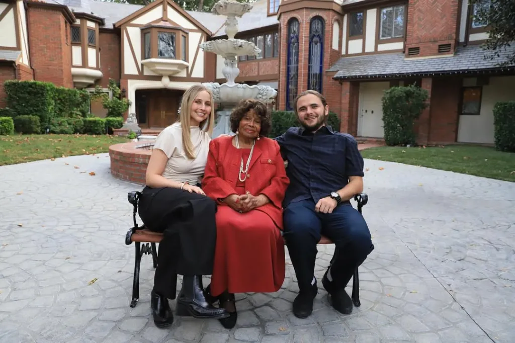 Molly Schirmang, Katherine Jackson, and Prince Jackson sitting on a bench outdoors.