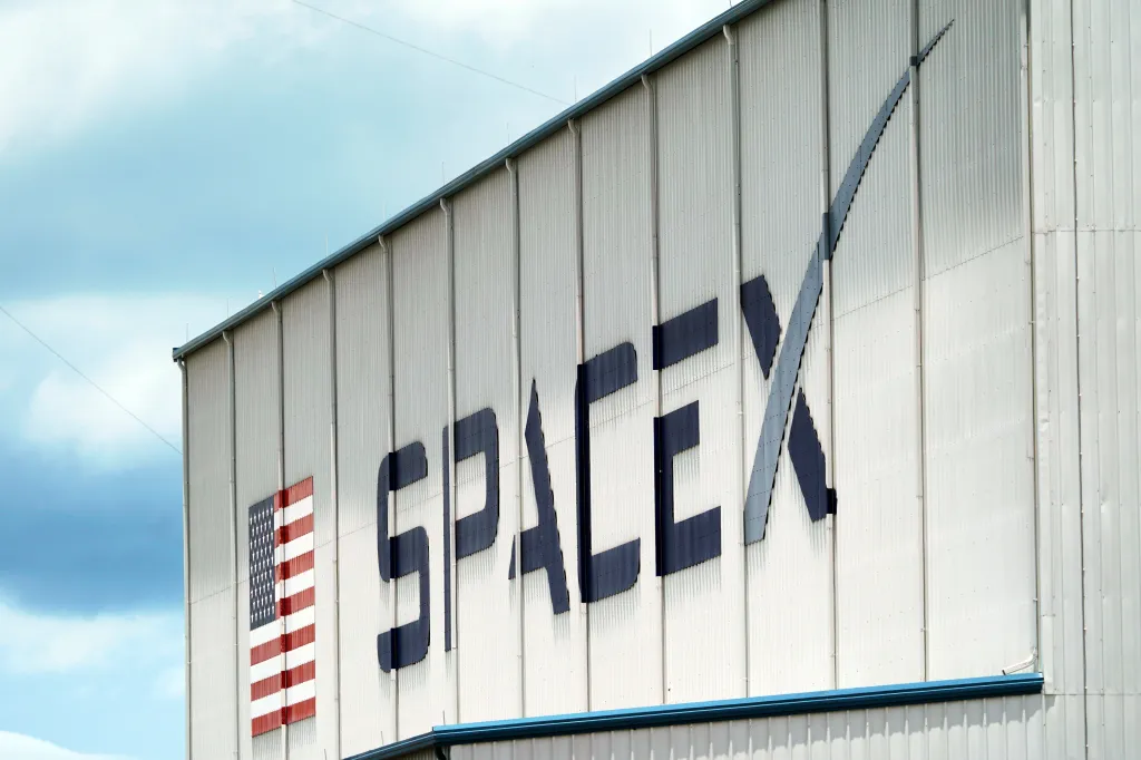 The SpaceX logo and an American flag displayed on a building.