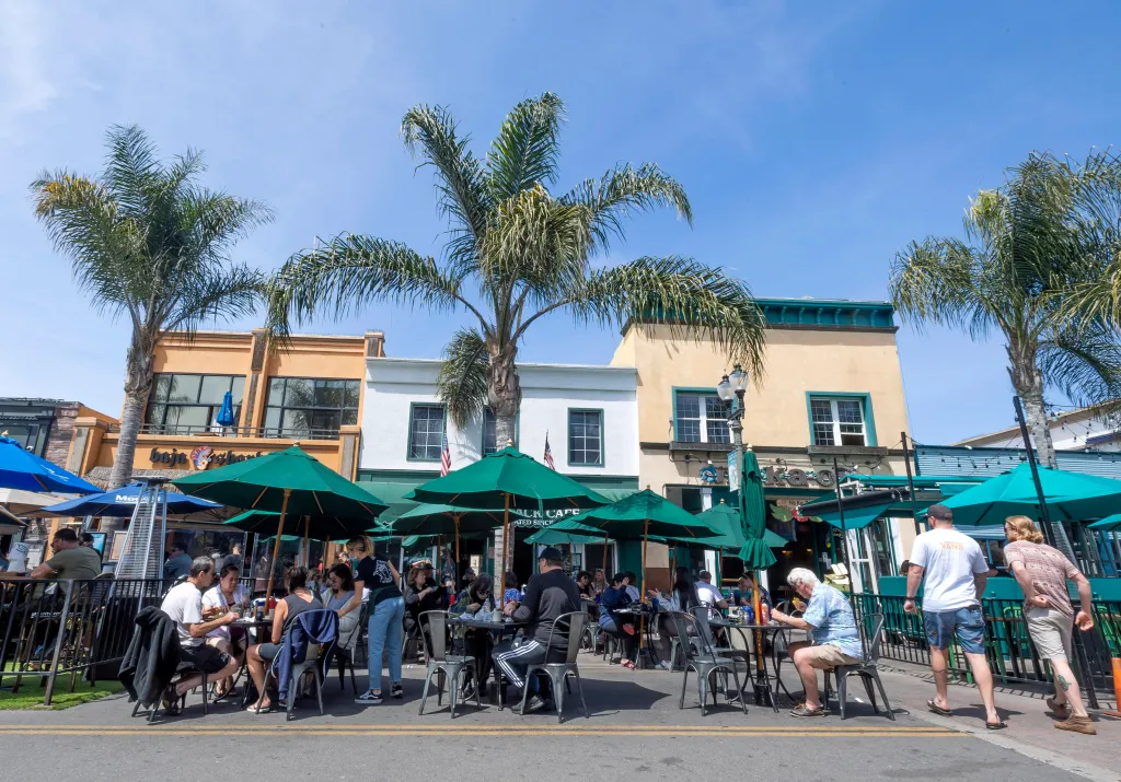 People dining outdoors along Main Street in Huntington Beach, California.