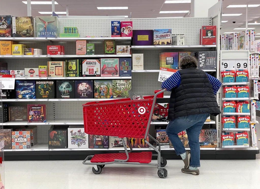 A customer with a Target shopping cart looks at a display of board games in a Target store.